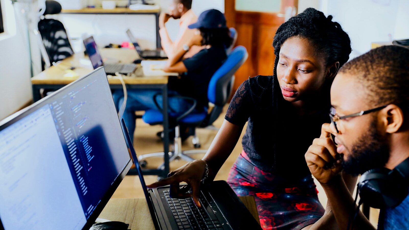 Two colleagues working through code together at a monitor